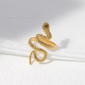 Macro shot of gold snake ring with hammered texture finish on white fabric background