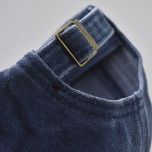 Detail of adjustable brass buckle and washed navy blue cotton fabric on baseball cap