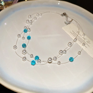 Detailed view of triple-layered pearl and blue crystal bead necklace on ceramic tray