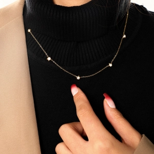 Detail of a gold necklace with five-pointed star pendants on a black turtleneck