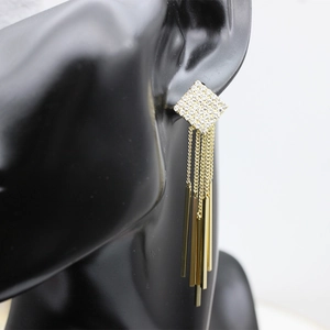 Close-up of golden square stud earrings with long metal tassels on black ear mannequin