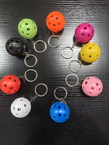 Top view of colorful hollow golf ball keychains arranged on a dark wooden surface