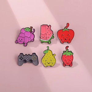 Detailed view of six fruit and game controller shaped enamel pins on a pink surface