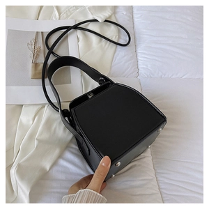 Close-up of black PU leather box bag featuring metal feet and structured geometric design