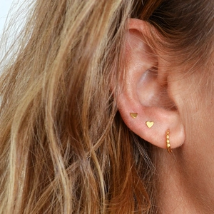 Minimalist gold heart stud earrings and beaded hoop earring set worn on ear