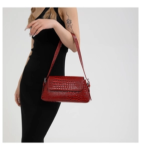 Detailed view of red crocodile pattern shoulder bag with silver metal hardware on a model
