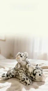 Detailed view of large and small snow leopard plush toys with soft white fur and blue eyes