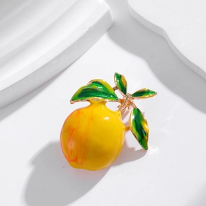 Cute enamel lemon brooch pin with green leaf and gold stem on white stone background