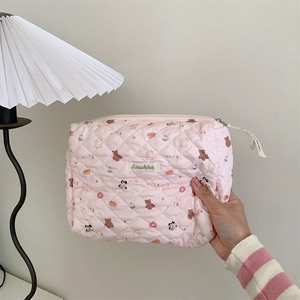 Trousse à maquillage rose matelassée avec motifs animaux tenue à la main montrant la texture