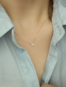 Detailed view of 14k gold clover pendant with sparkling white stones on neck