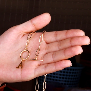 Minimalist gold paperclip chain necklace with OT buckle and letter A pendant on hand