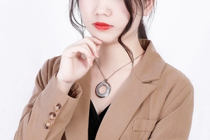 Detail of silver hollow circle pendant necklace worn by a model in brown blazer