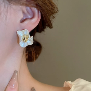 Close-up of French style gold flower earrings with white petals on a model's ear