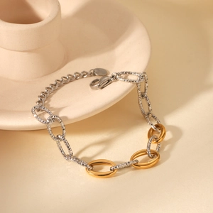 Detail of two-tone gold and silver link chain bracelet with hammered texture and lobster clasp