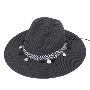 Close-up of black wide brim straw hat with bohemian geometric band and silver coin tassels