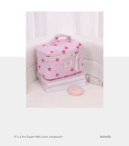 Detail of pink strawberry quilted makeup bag with double zippers and soft ribbon handle