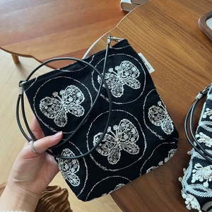 Close-up of black canvas bag featuring white butterfly embroidery and metal ring handle