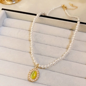 Vue macro d'un collier de perles rétro avec pendentif ovale doré et pierre jaune-vert