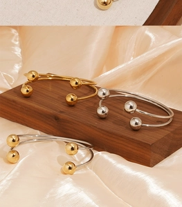 Three minimalist stainless steel ball open bangles in gold and silver on silk fabric