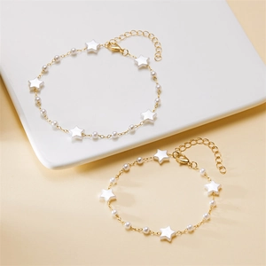 Detail of gold ankle bracelet featuring artificial pearls and white star charms