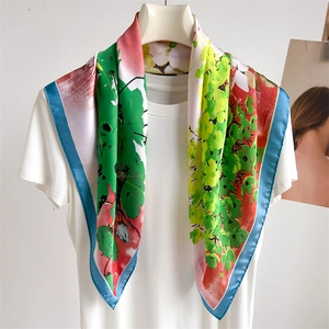 Silk square scarf with grape leaf print draped elegantly over a white crewneck shirt