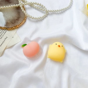 Gros plan de supports de téléphone souples en forme de pêche rose et poussin jaune sur tissu