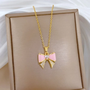 Detail of pink enamel bow necklace with heart diamond pendant on gold chain