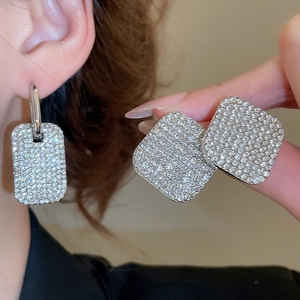 Dettaglio di orecchini a lobo quadrati argento e pendente rettangolare con strass lucidi