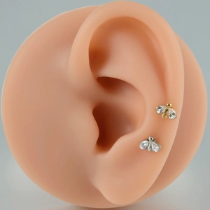 Titanium bee ear studs with zircon wings in gold and silver finish on ear model