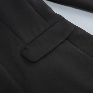 Close-up of black blazer flap pocket detail showing premium woven fabric and stitching