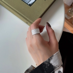 Detailed view of a wide brushed 925 silver ring on a finger with a minimalist background