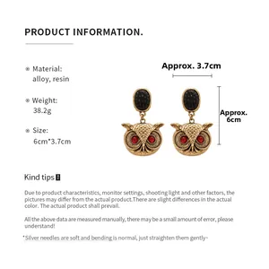 Detailed view of vintage gold owl earrings with red resin eyes and product dimensions