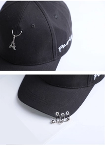 Detail of black cotton baseball cap with Paris embroidery and silver metal rings on brim
