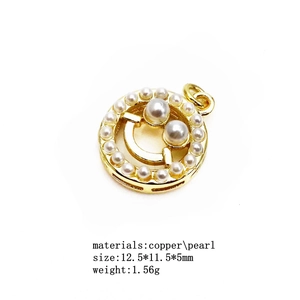 Detailed view of a gold-plated copper pendant with pearl-inlaid smiley face design