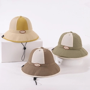 Detail view of colorful patchwork kids bucket hats with leather logo and windproof ropes