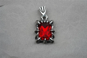Macro shot of rectangular red gemstone secured in silver claw setting on steel pendant