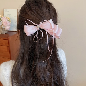 Detail of elegant pink satin bow hair claw clip with crystal on textured hairstyle