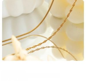 Macro shot of gold-plated double-layer snake and twist chain necklace with mirror reflection