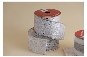 Detail of silver glitter swirl patterns on white mesh Christmas ribbon for DIY crafts