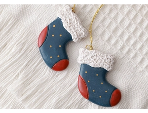 Detailed view of red and blue Christmas stocking pendants with gold dots on a white knit background