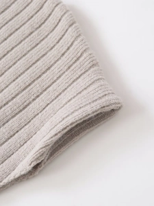 Close-up of gray ribbed knit texture with soft wool fibers on an asymmetric belt top
