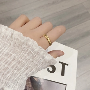 Detail of gold heart-shaped stacking ring shown on hand with elegant white sleeve backdrop