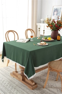Close-up of dark green washed cotton tablecloth with white pom-pom fringe edges