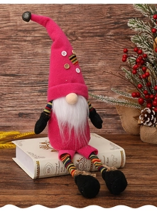 Pink Christmas gnome with long legs and tall hat sitting on books with pine decor