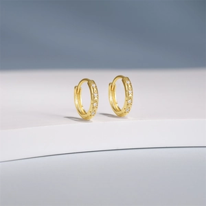 Detail of gold star earrings with cubic zirconia on a white geometric stand