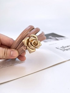Detail of pink leather wrap bracelet with a three-dimensional golden rose clasp buckle