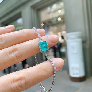 Detail of silver bracelet with emerald-cut green gemstone and sparkling zircon crystals