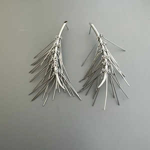 Dettaglio degli orecchini a spillo color argento con lunghe frange e barre metalliche sottili