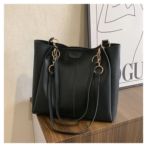 Detail of black PU leather tote bag with elegant gold metal ring and chain strap connectors
