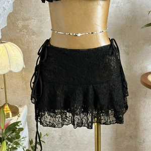 Detail of black mesh lace skirt with drawstring ties and ruffled hem on a model stand